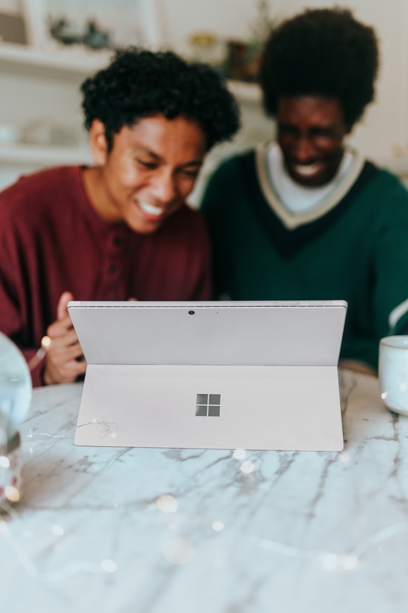 Two people laughing while looking at a Surface laptop screen